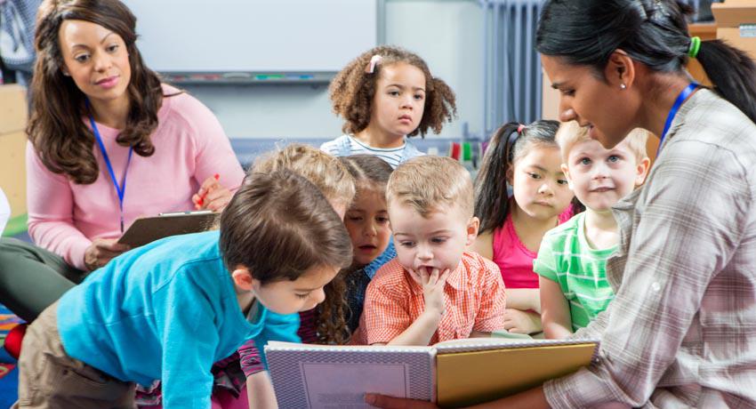 Teacher reading book to young kids