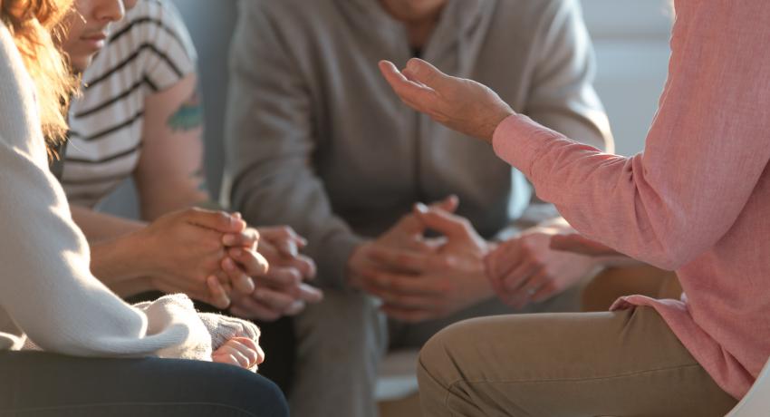 Group of young people meet with a facilitator. 