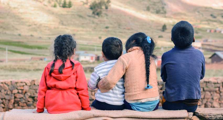 children sitting on a wall towards landscape